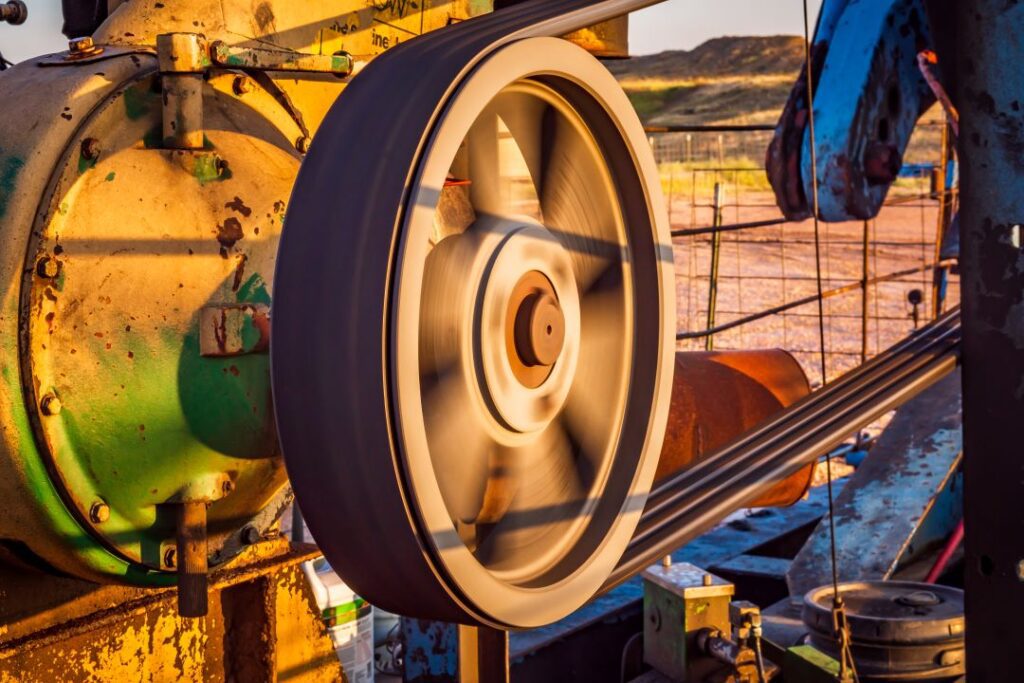 close up view of a spinning pulley that is driving a pumpjack oil pump